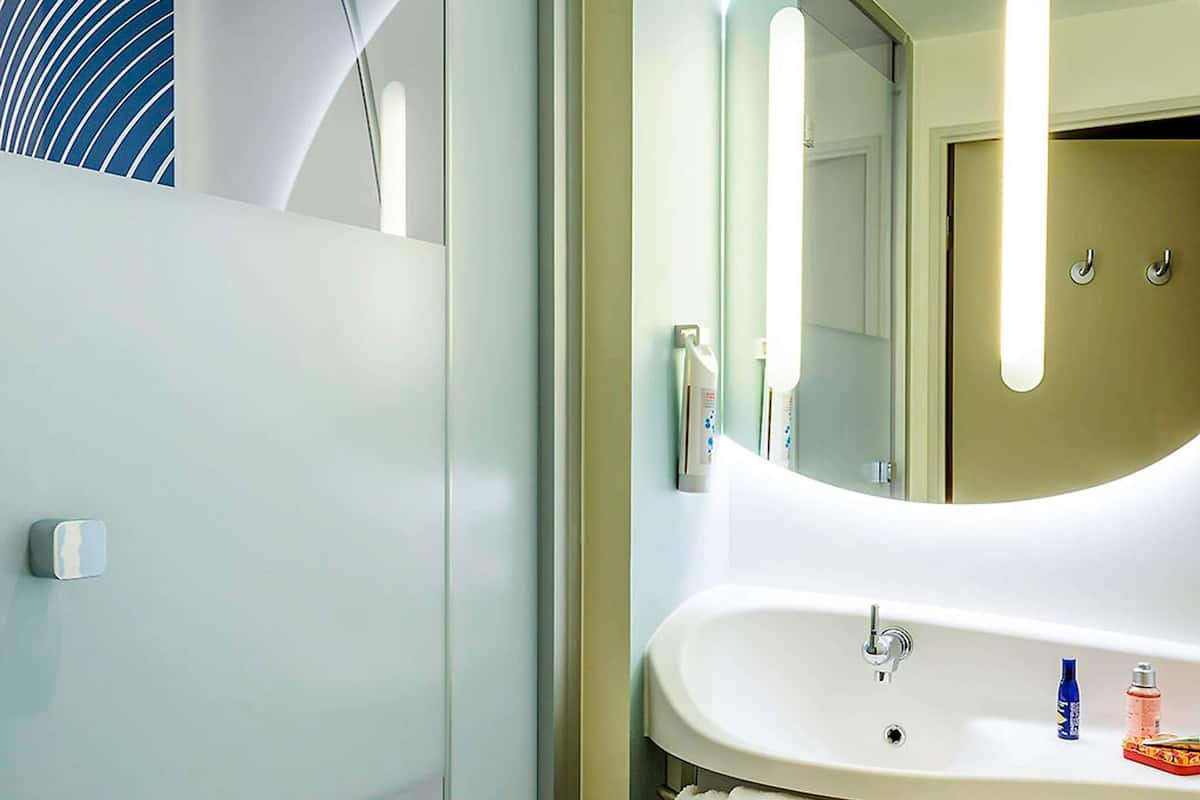 A bathroom with a white sink, a mirror, and a towel rack.