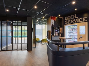 Un intérieur moderne comprenant une machine à café, un coin salon et un distributeur automatique.