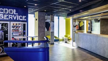 A modern interior with a vending machine labeled 'COOL SERVICE,' seating areas, and a reception desk.