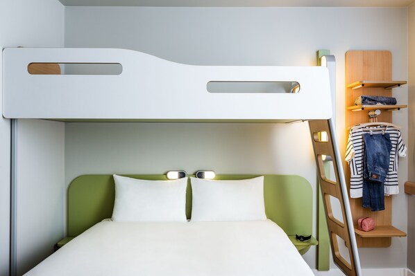 A bunk bed with a green headboard and white bedding, a ladder, and a shelf with clothes and a bag. - ibis budget Saint Quentin en Yvelines Velodrome (Montigny-le-Bretonneux)