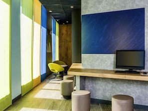 A modern office space with a long corridor, a wooden desk with a computer, and a yellow chair. - ibis budget Saint Quentin en Yvelines Velodrome (Montigny-le-Bretonneux)