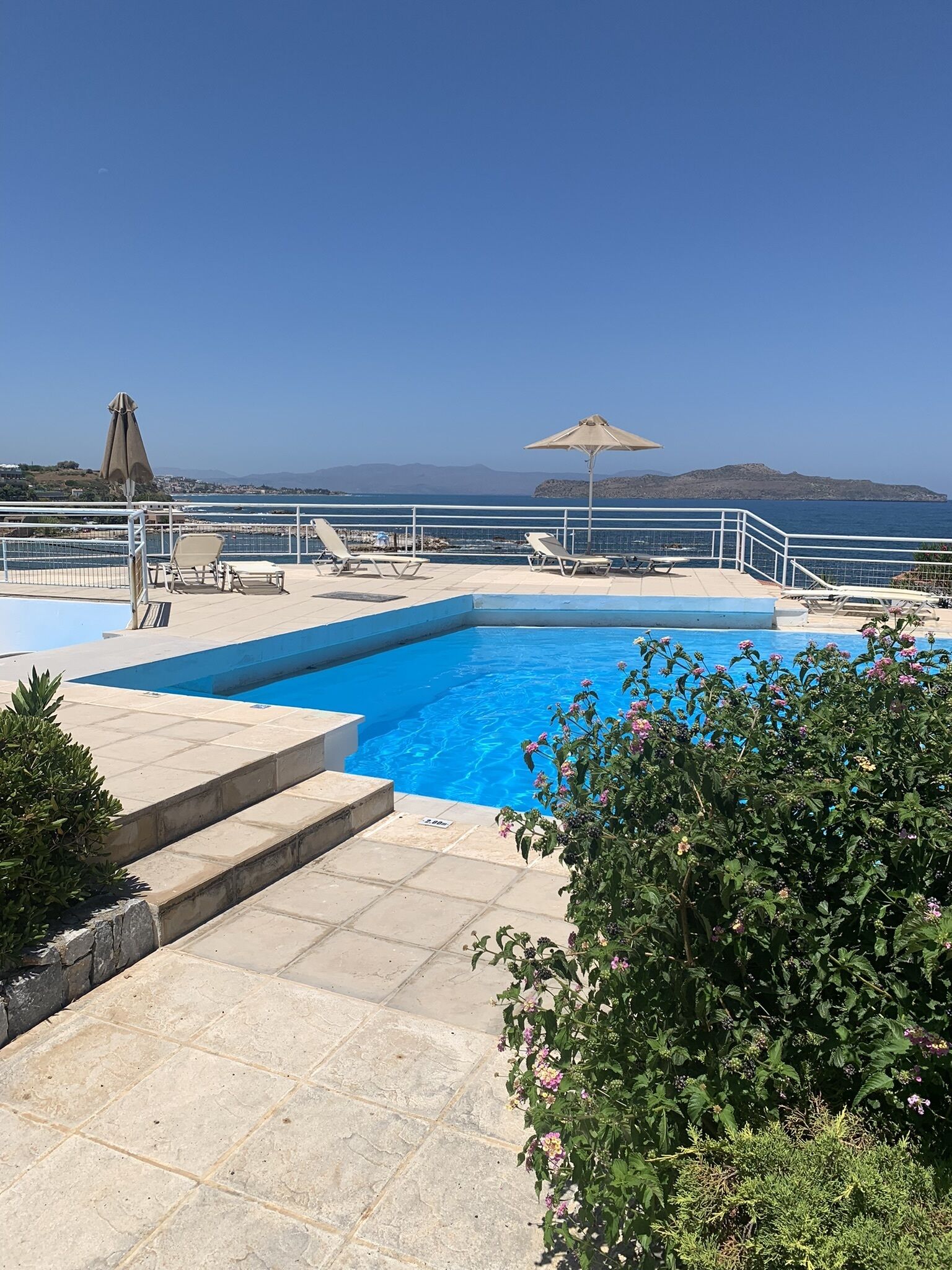 A swimming pool with a view of the sea and mountains.
