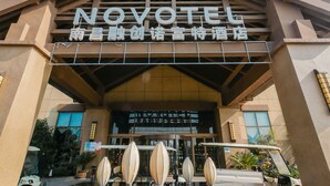 The NOVOTEL building with a prominent entrance, steps leading up to the entrance, and a clear blue sky in the background. - Novotel Nanchang Sunac (Nanchang)