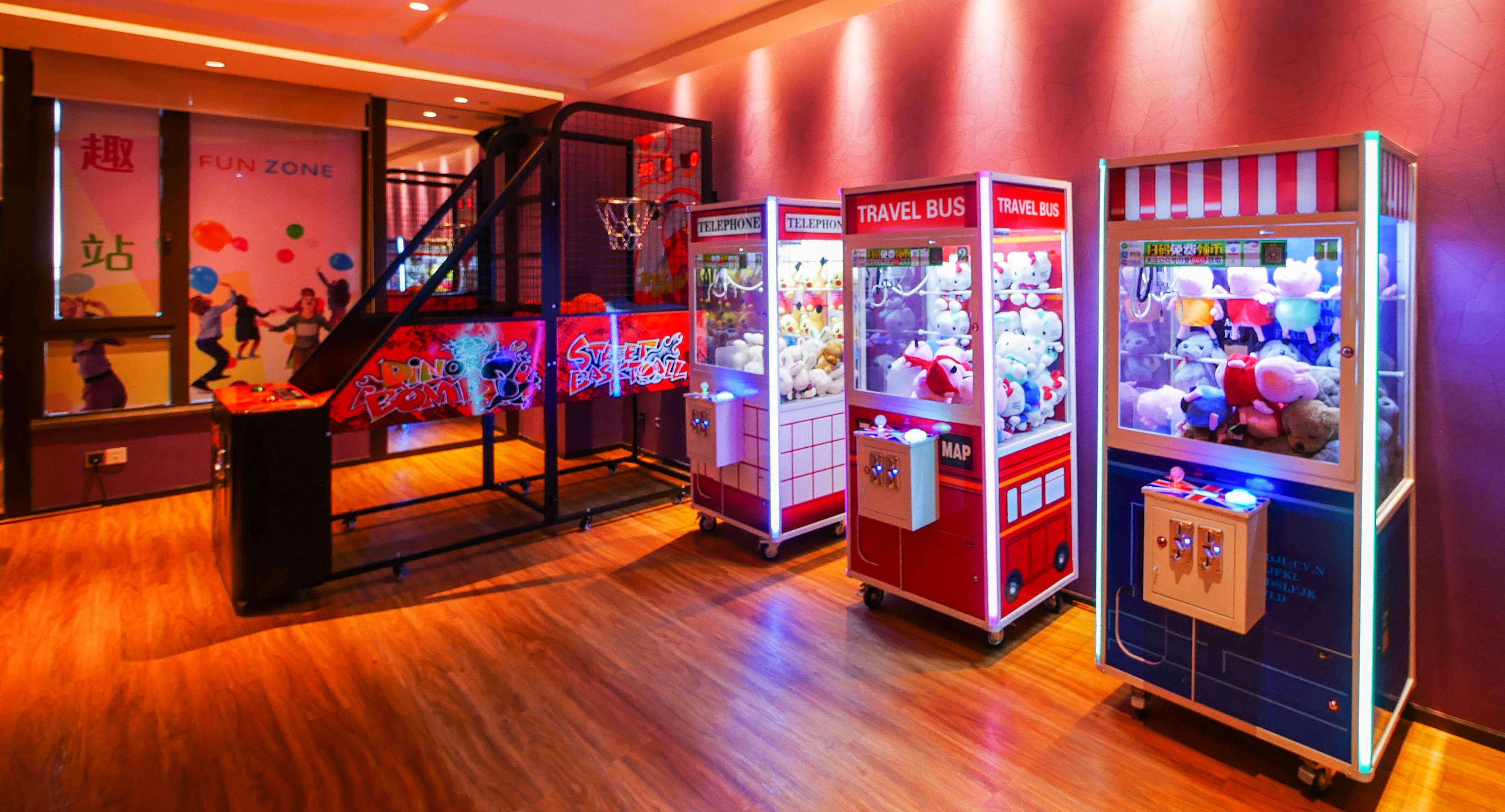 Ein hell erleuchteter Arcade-Bereich mit Krabschere-Automaten und einem Basketballfeld.