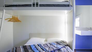 A bunk bed with a white headboard, a hanging clothes rack, a white bedside table with a mirror, and a blue accent wall.