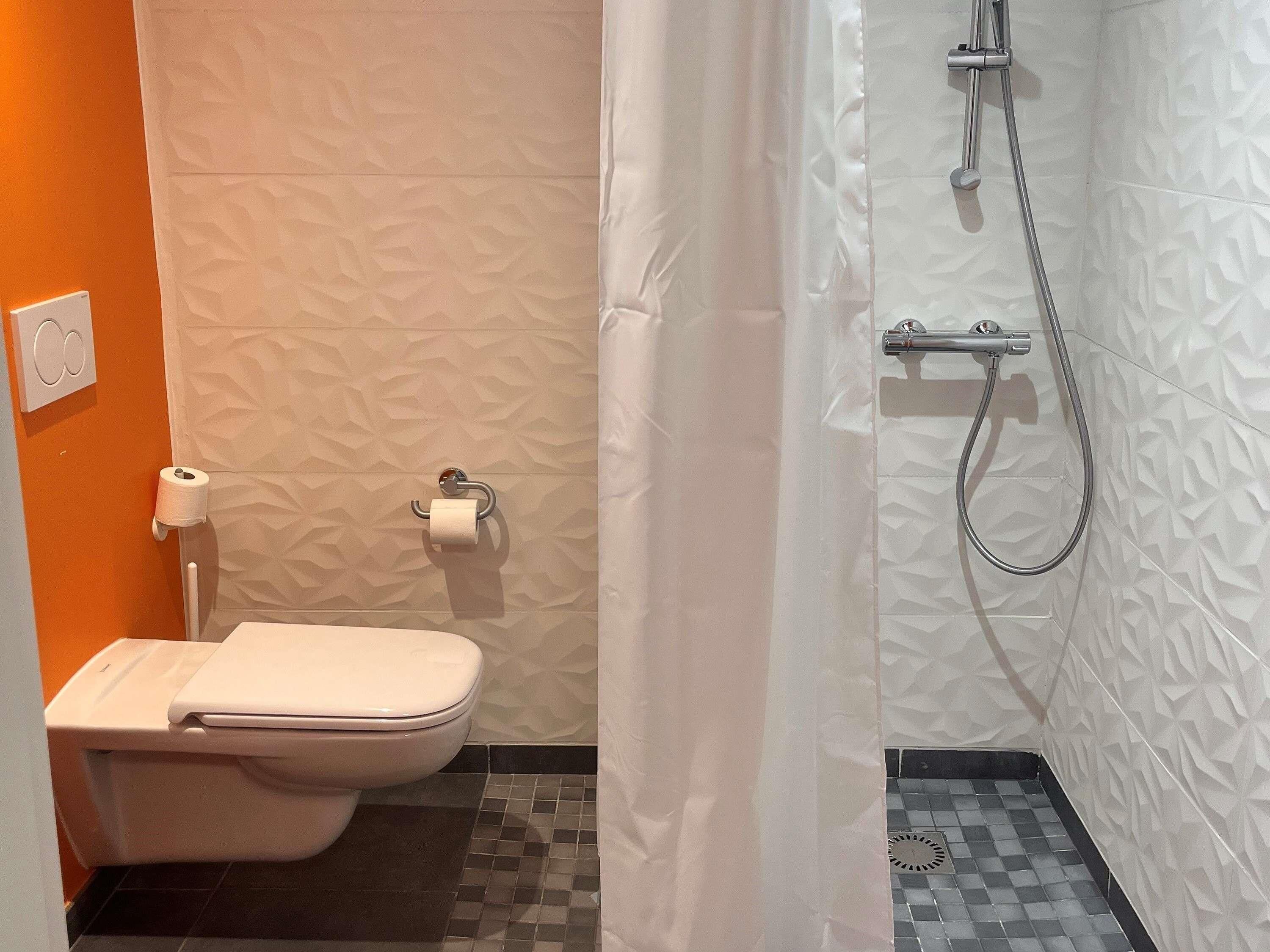 Une salle de bain avec des toilettes, une douche et des murs décorés de motifs.