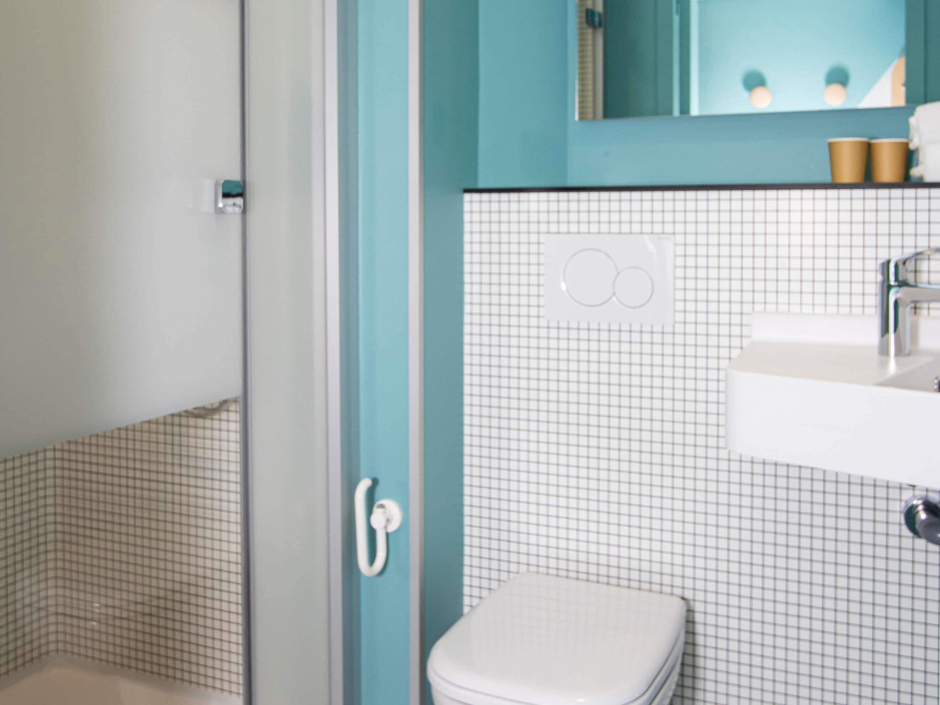 A bathroom with a white toilet, a sink with a mirror above it, and a shower area.
