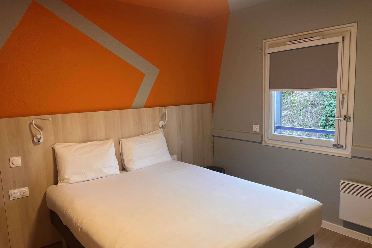 Une chambre à coucher avec un lit, une fenêtre et un radiateur fixé au mur.