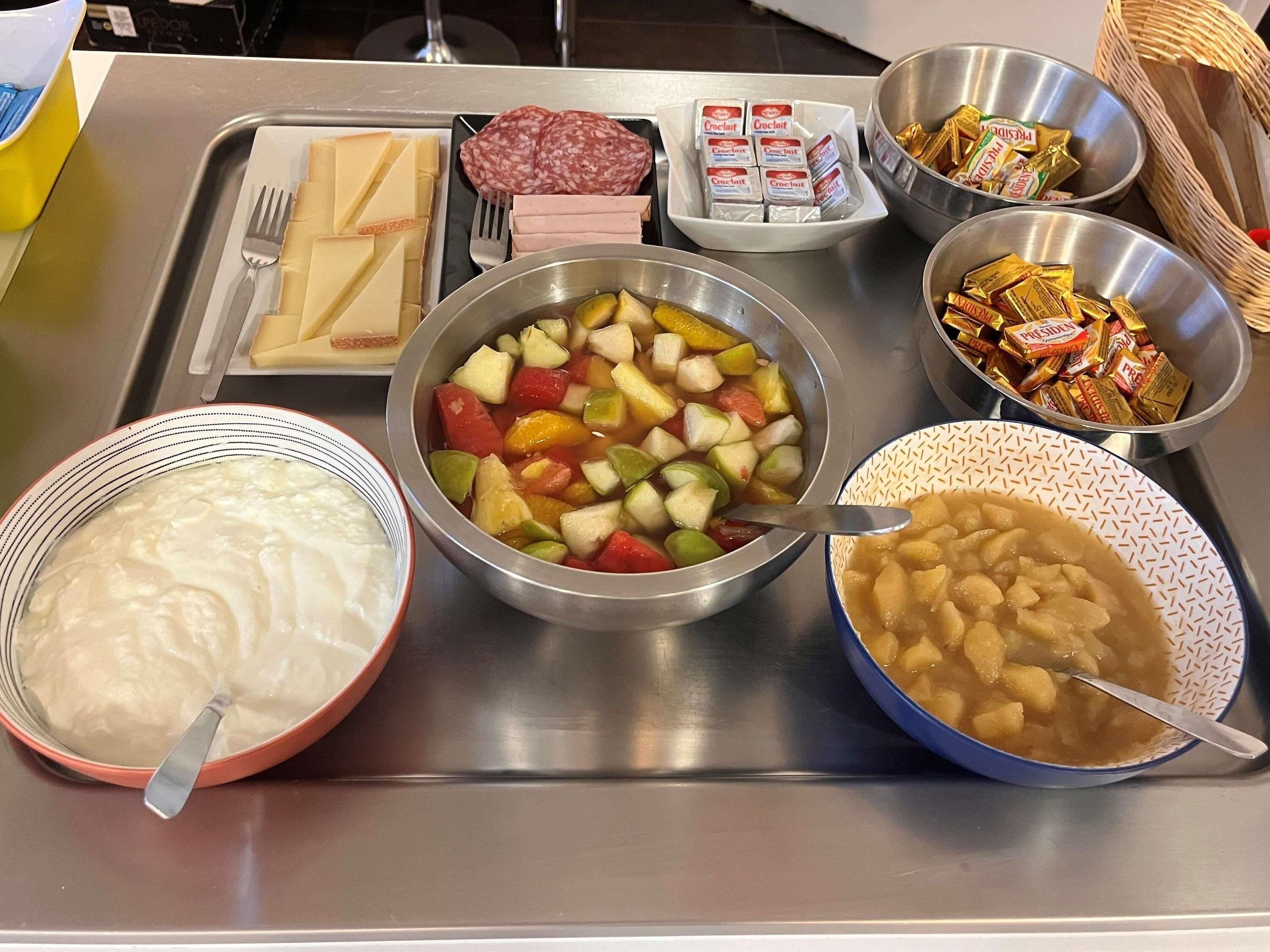 Une table de buffet proposant une variété d’aliments, notamment des fruits, des légumes, de la viande et des condiments.