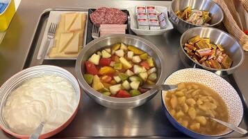 Une table de buffet proposant une variété d’aliments, notamment des fruits, des légumes, de la viande et des condiments.