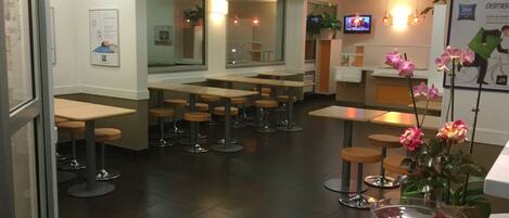 A restaurant interior with tables and chairs, a television, and a poster on the wall.