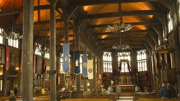A church interior with wooden pews, stained glass windows, and a high vaulted ceiling.