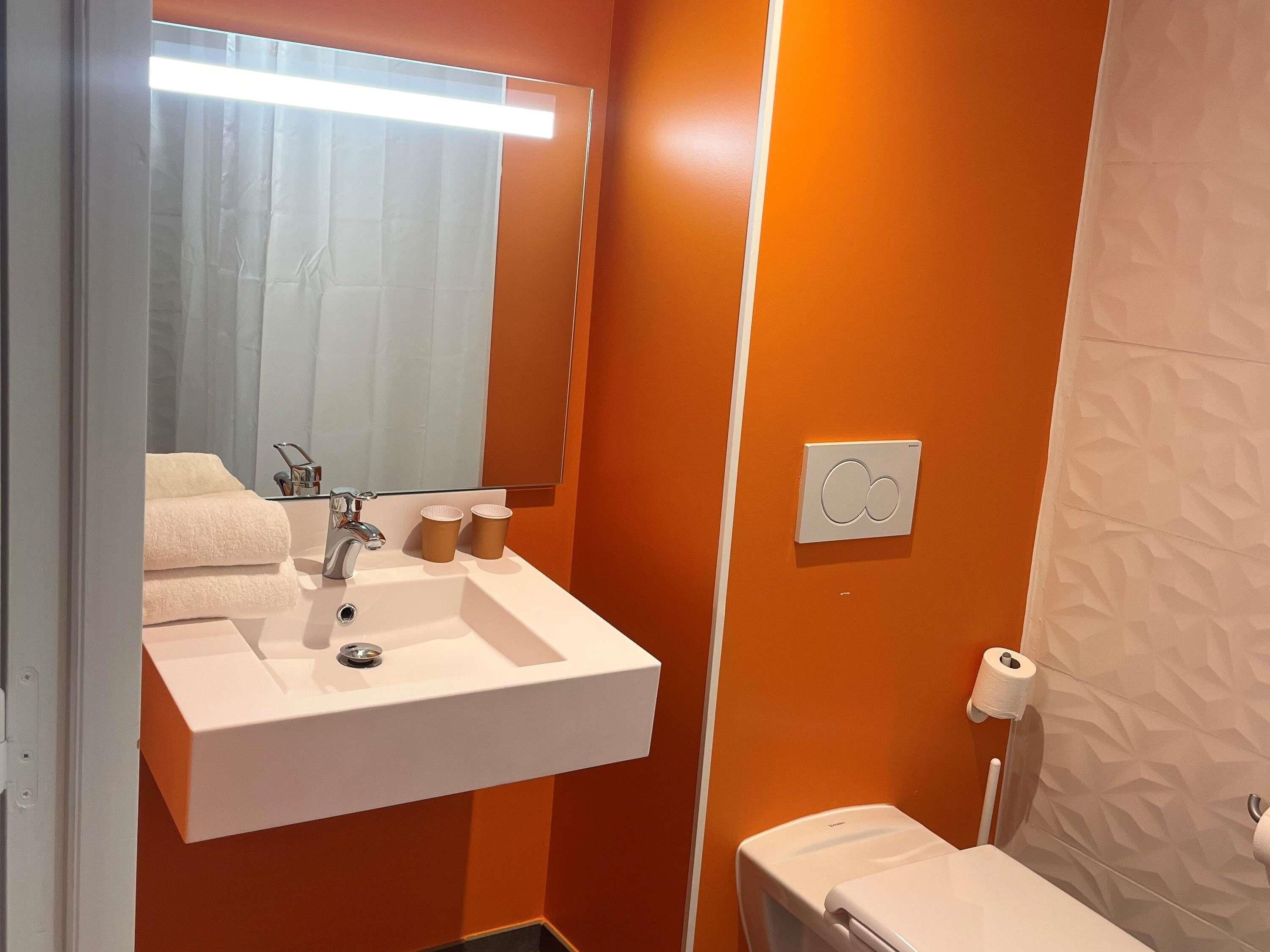 A bathroom with a white sink, mirror, and toilet.