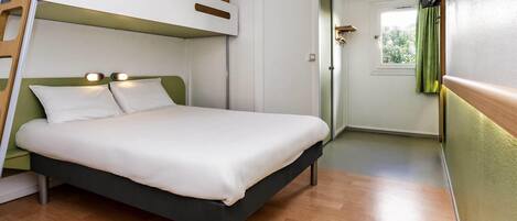 Una cama litera con cabecera, una mesita de noche y un televisor instalado en la pared.