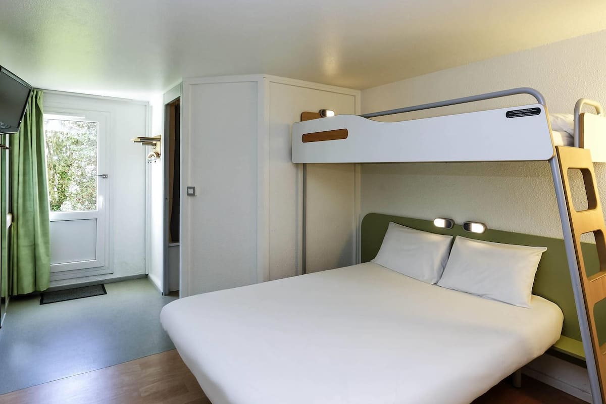 A bunk bed with a headboard, a bedside table, and a door leading to a bathroom.