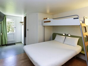 A bunk bed with a headboard, a bedside table, and a door leading to a bathroom. - ibis budget Lorient Caudan (Caudan)