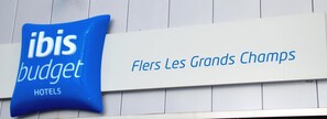 Un letrero para hoteles ibis budget con el nombre 'Fleurs Les Grands Champs'.