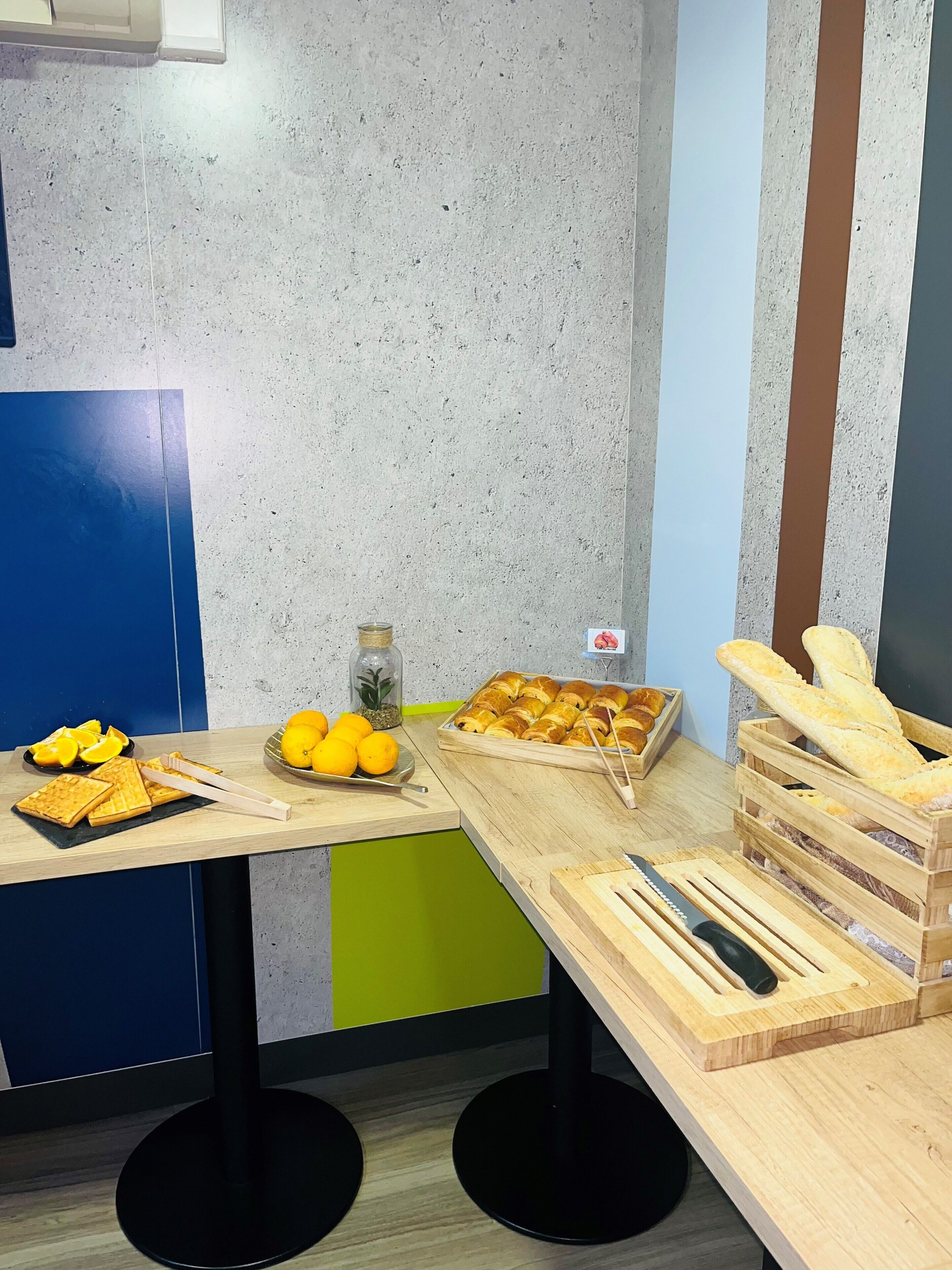 Un plateau de petit-déjeuner avec des gaufres, des oranges et des croissants, disposé sur une table en bois.