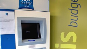 An ibis budget hotel self-service kiosk with a digital screen, card slot, and a small display. - ibis budget Flers Les Grands Champs (Flers)