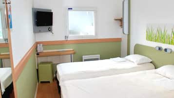 Habitación de hotel con dos camas, televisión, ventana, calefactor y una mesita.