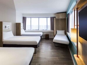 Habitación de hotel con dos camas individuales, un televisor, una mesita de noche, una ventana con cortinas y suelo de madera.