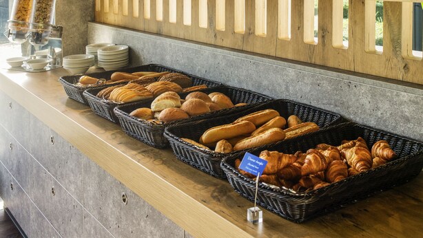Een ontbijtbuffet met verschillende soorten fruit, gebak en brood, gepresenteerd op houten planken.