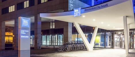 El exterior del hotel ibis budget en Ámsterdam Ciudad Sur, con una fachada moderna, una entrada destacada con toldo y una zona de aparcamiento para bicicletas.