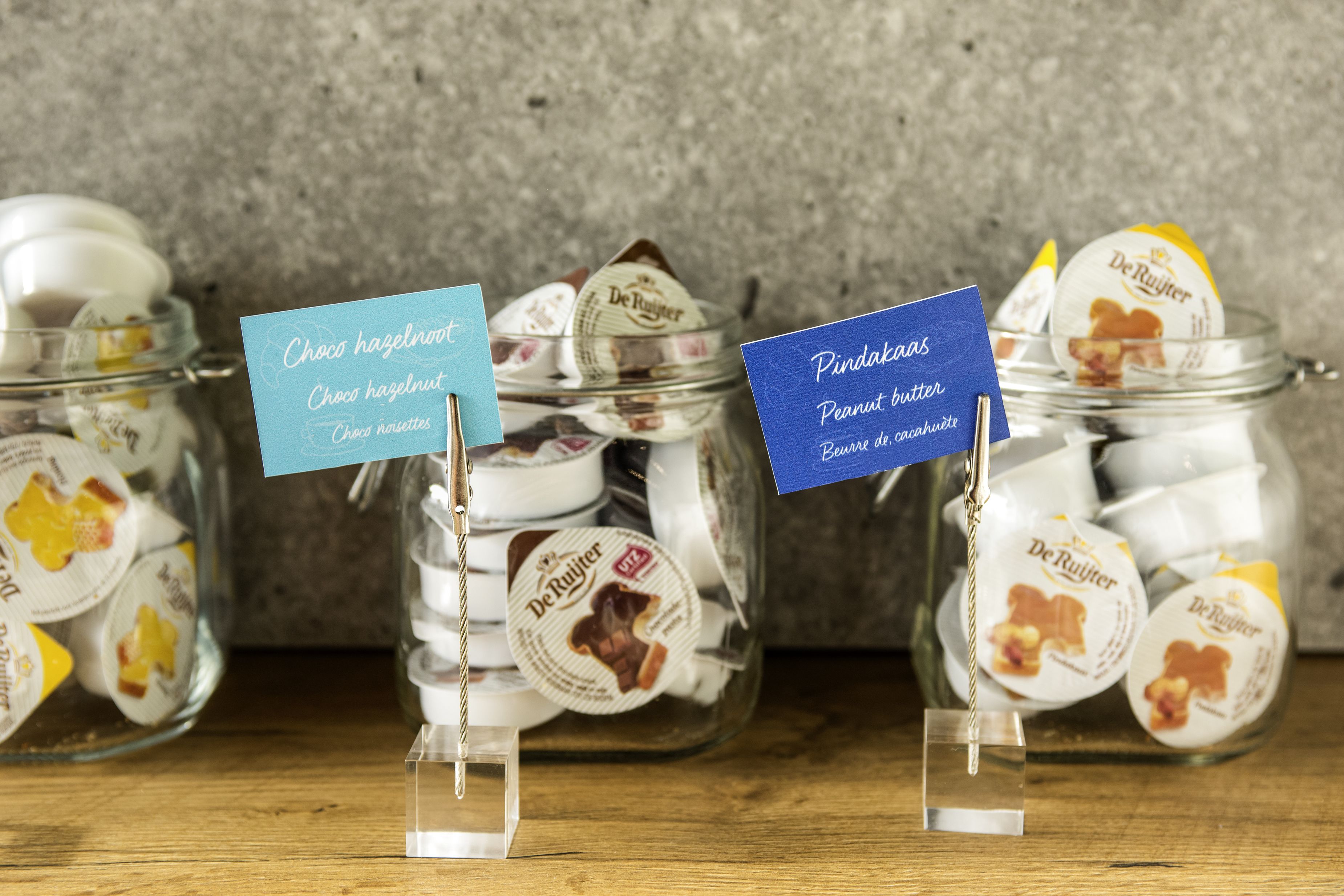 Three glass jars with labels indicating different types of chocolates and peanut butter.