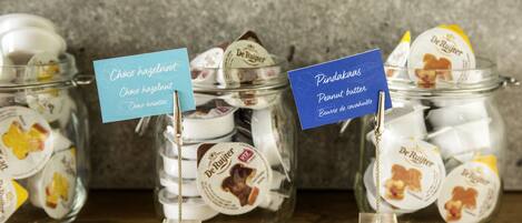 Three glass jars with labels indicating different types of chocolates and peanut butter.