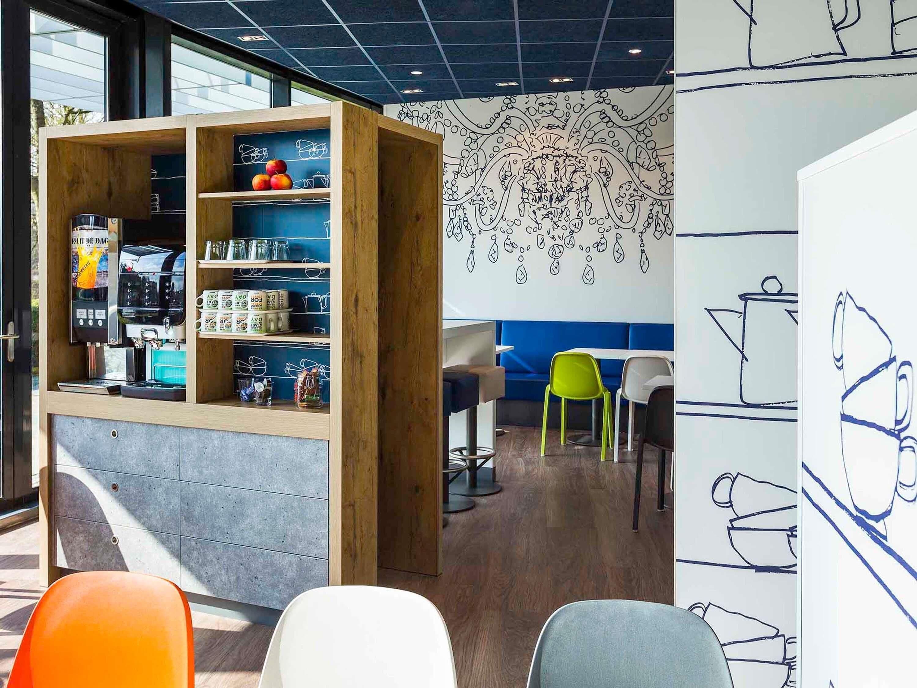 A café with a wooden bookshelf, seating area, and a wall with abstract line drawings.