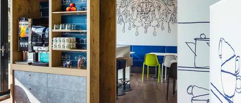 A café with a wooden bookshelf, seating area, and a wall with abstract line drawings.