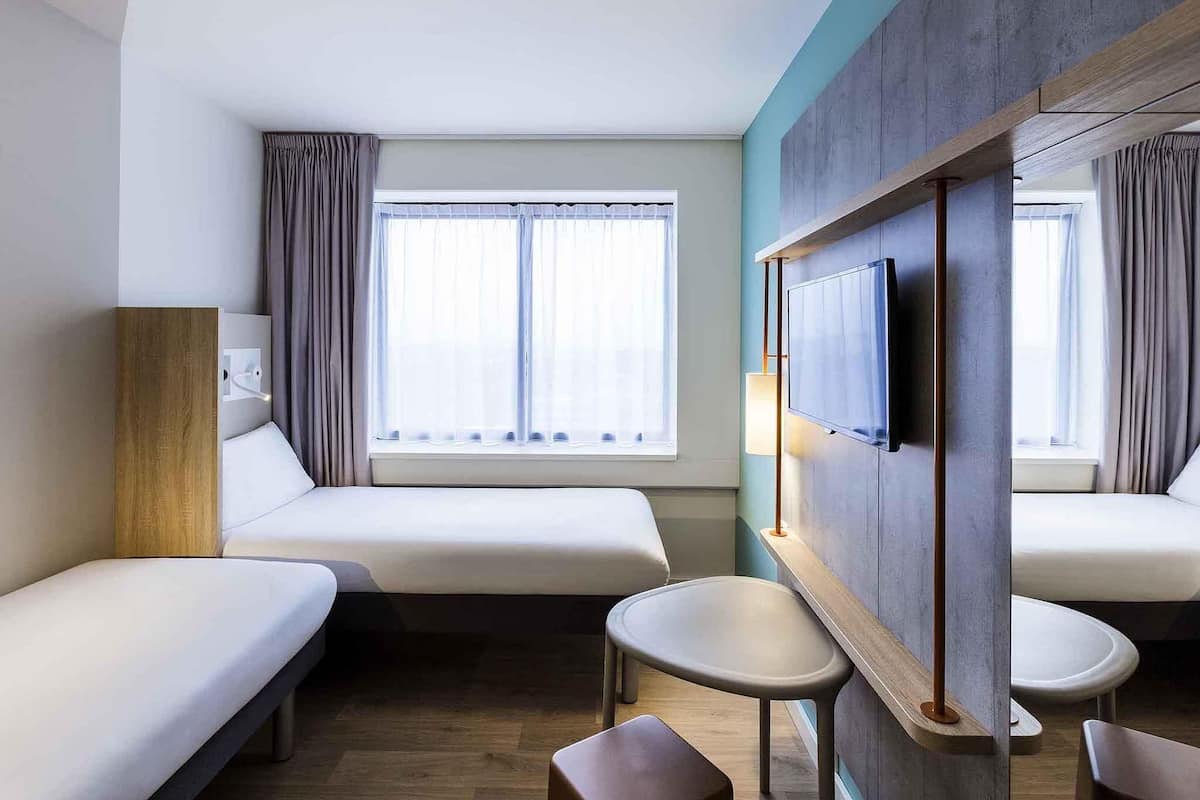 Una habitación de hotel con dos camas, un televisor y una mesita.