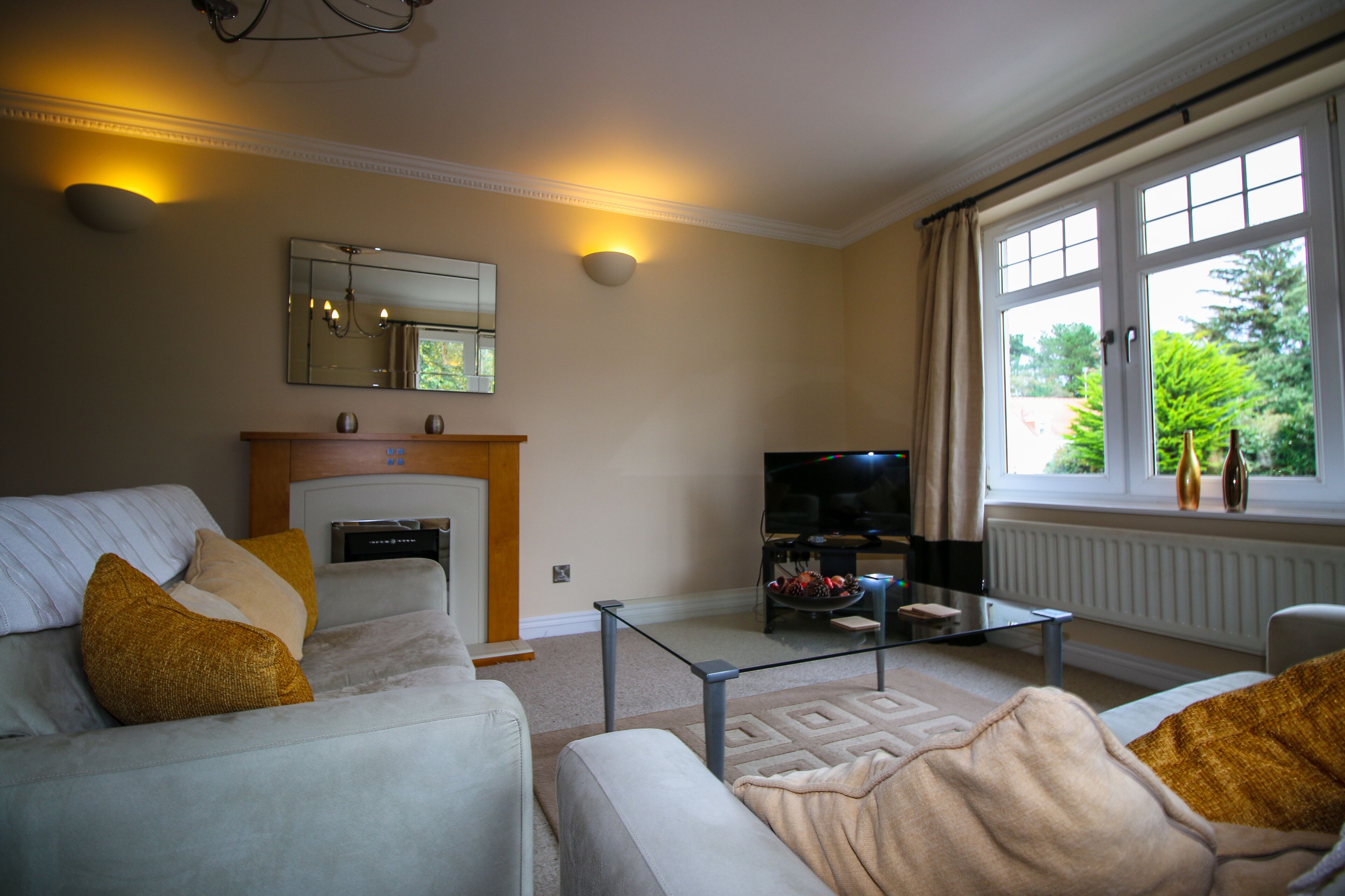 A living room with a fireplace, a television, and a window with curtains.