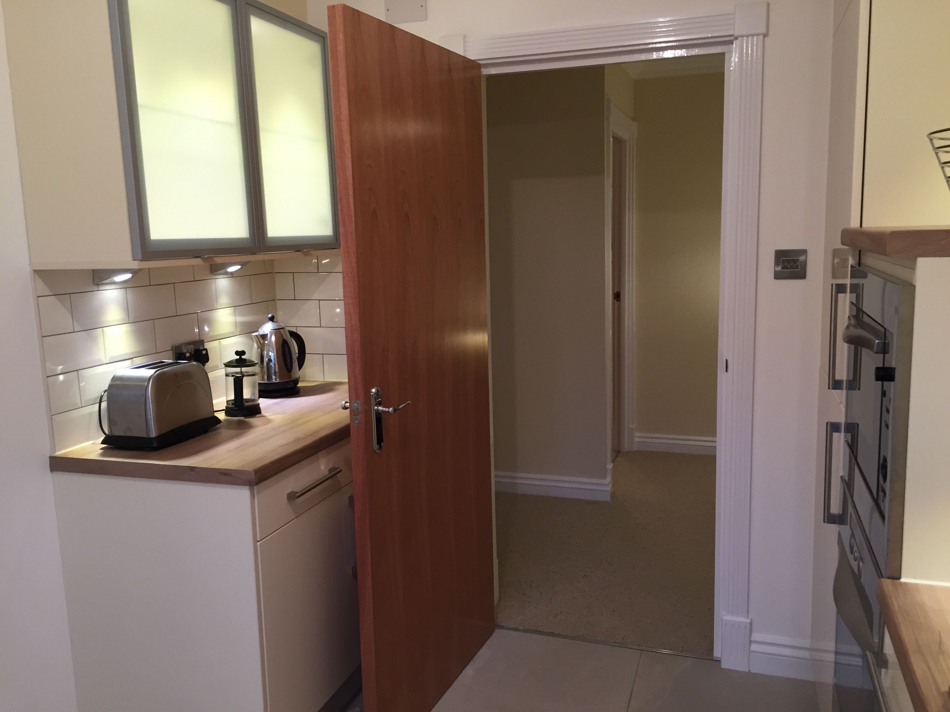A compact kitchen with a toaster, kettle, and cabinets.