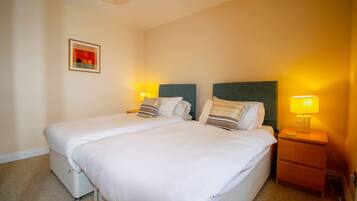 A double bed with white bedding, two bedside tables with lamps, and a framed picture on the wall.