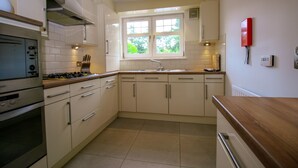 Una cocina con armarios blancos, una estufa y una ventana que da a vistas de follaje.