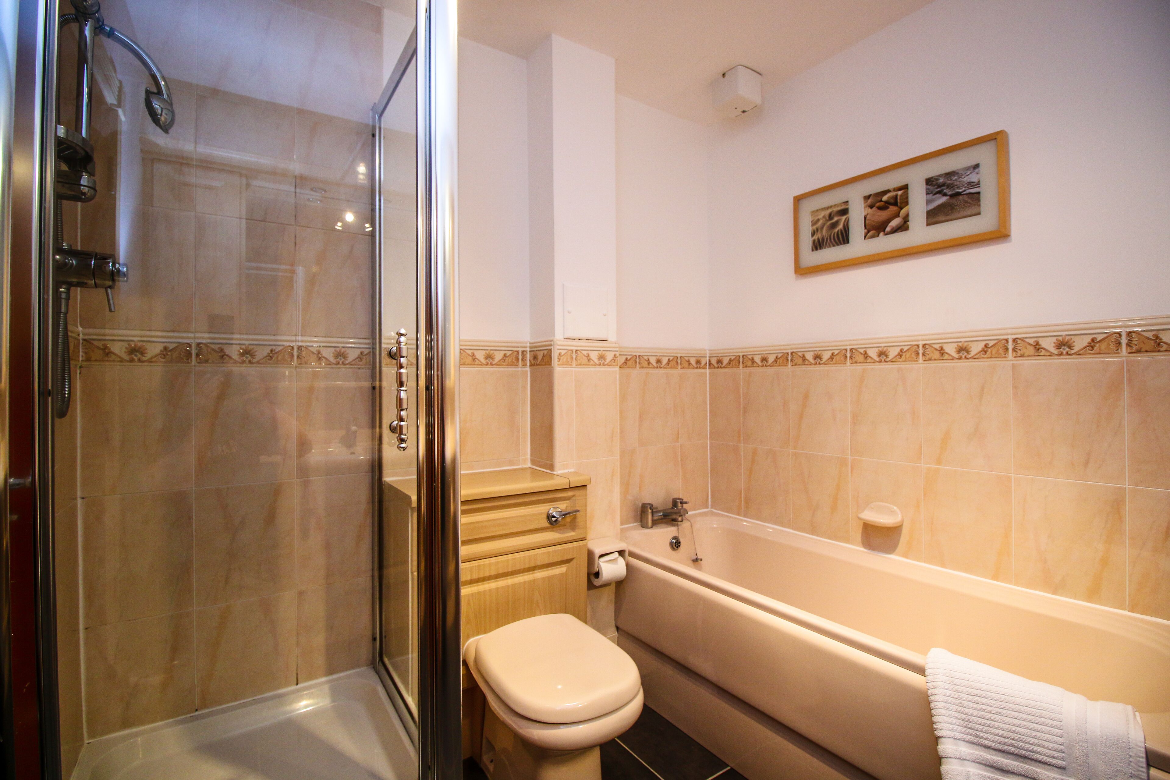 A bathroom with a glass-enclosed shower, a toilet, and a bathtub.