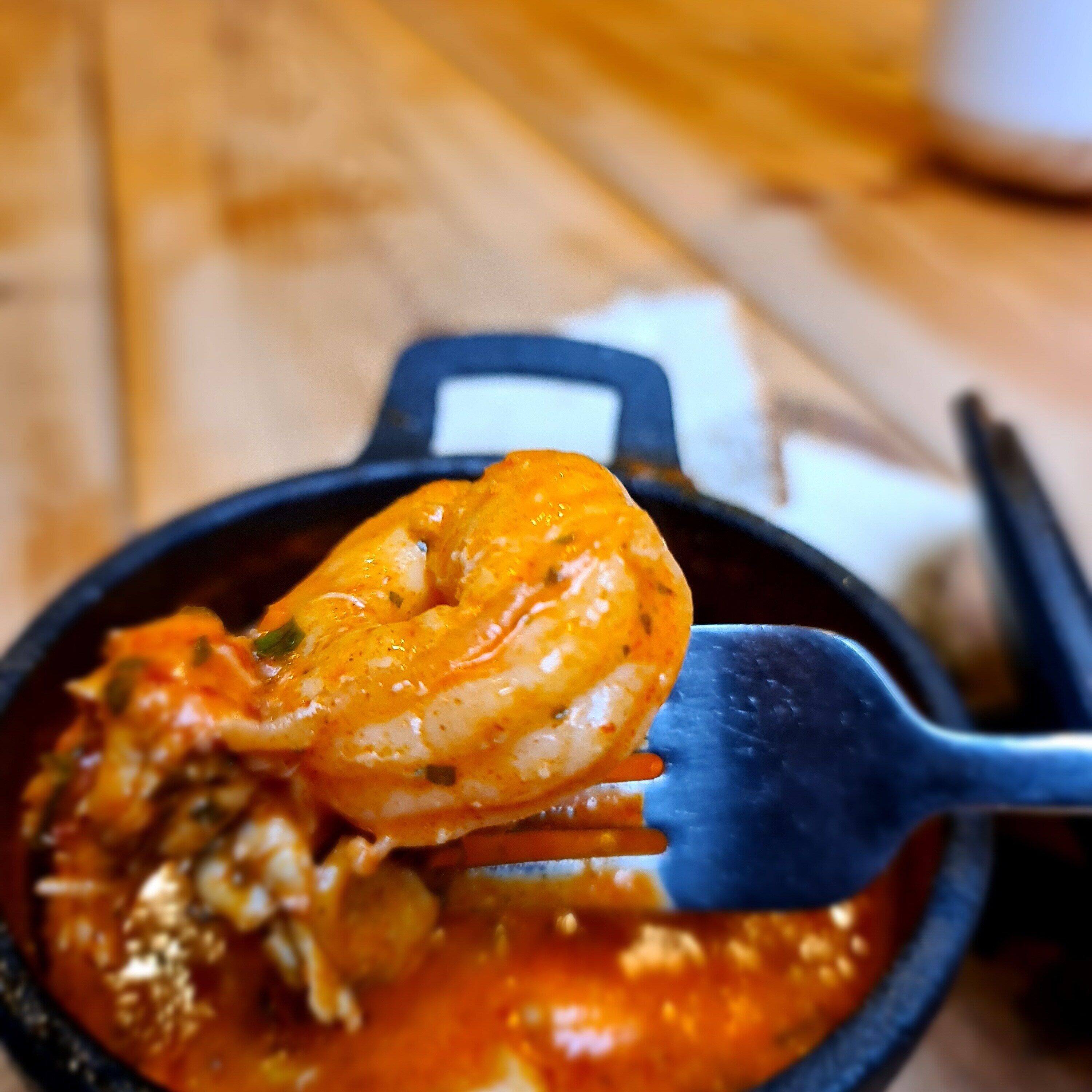A shrimp dish in a black bowl with a fork.