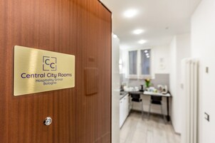 Puerta de una habitación de hotel con un cartel que indica que pertenece a Central City Rooms, parte del Hospitality Group, Bolonia.