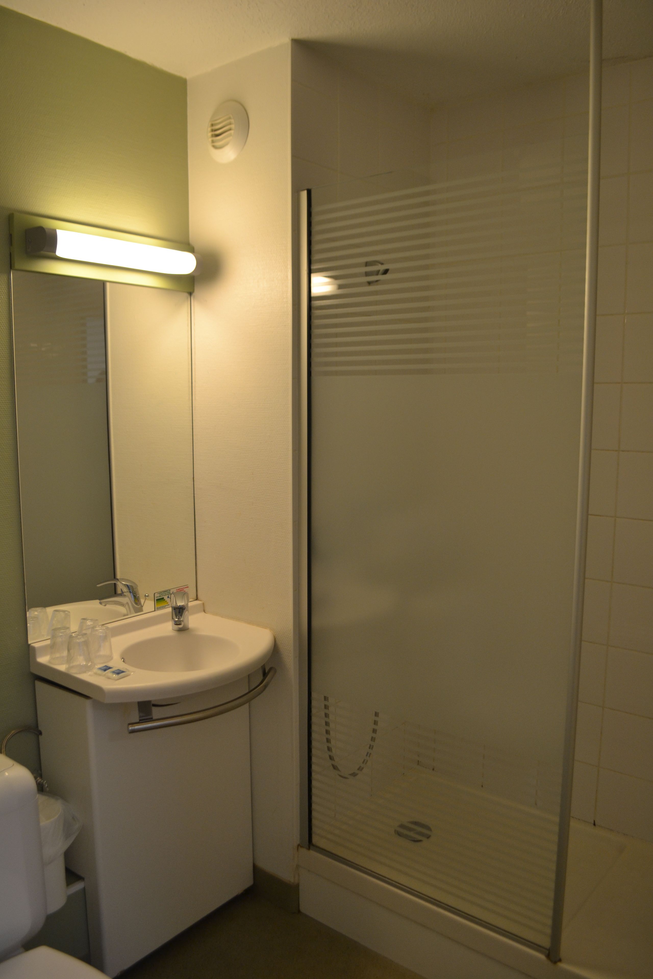 Een badkamer met een wastafel, spiegel en een douche met glazen wanden.