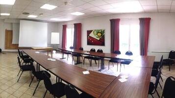 A conference room with a long table, chairs, and a projector screen.