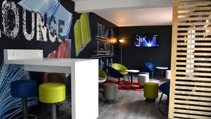 Zona de bar moderna con barra, taburetes y una pantalla de televisión que muestra una actuación.