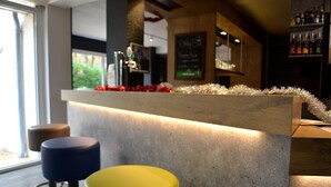Una zona de bar con mostrador de madera, menú en una pizarra y vistas al exterior.