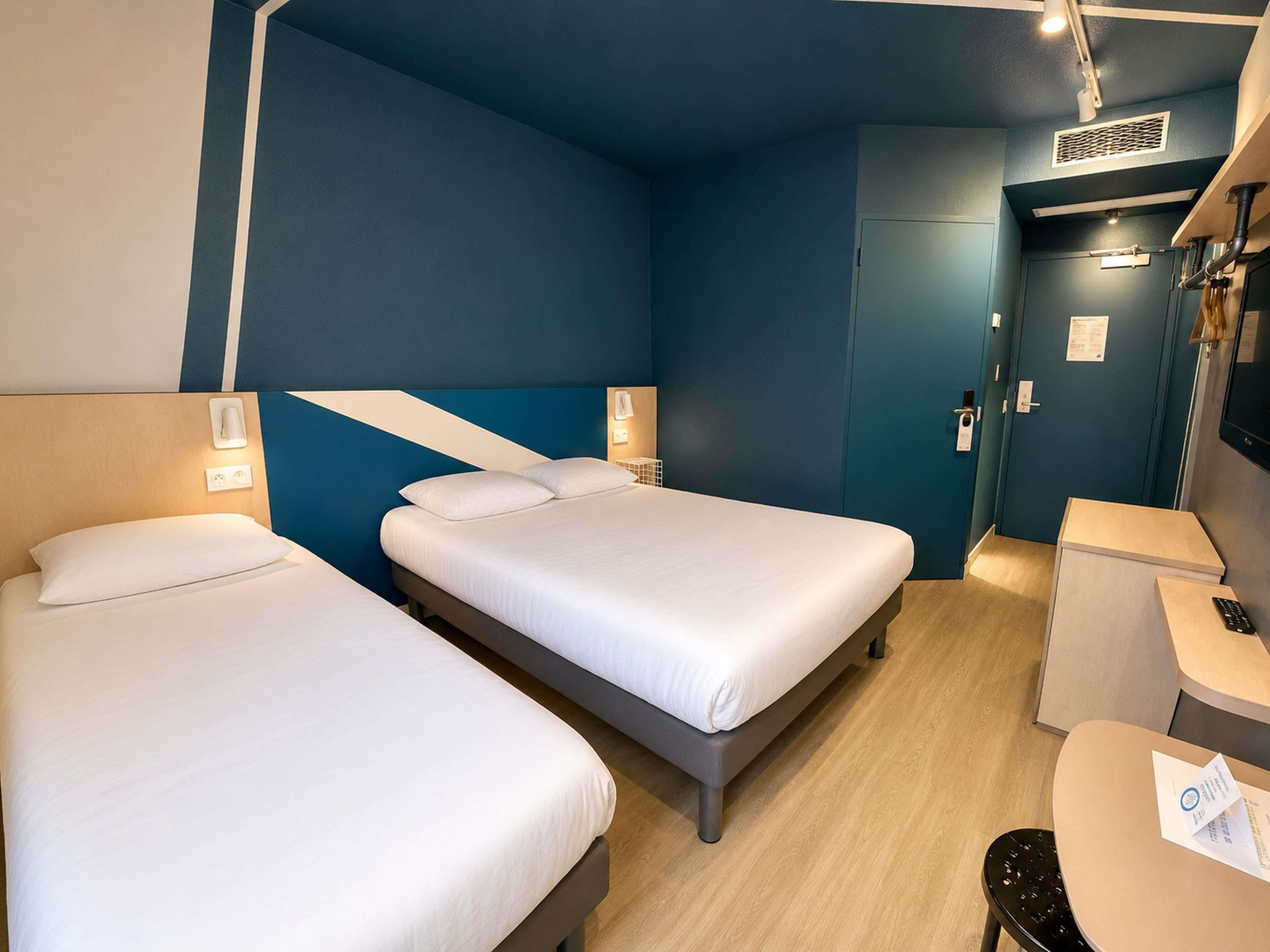 Habitación de hotel con dos camas, un escritorio y una silla.