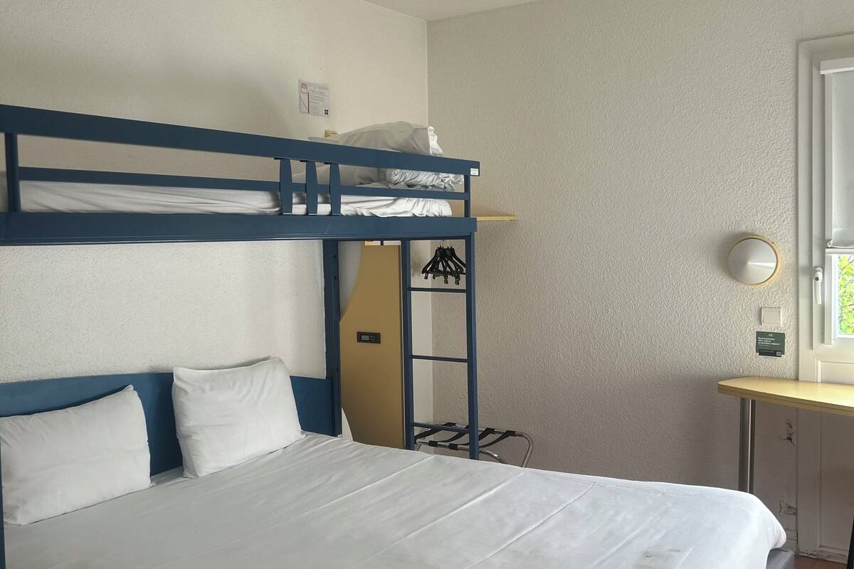 A bunk bed with a desk and chair, a window with a view, and a ceiling light.