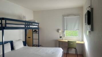 A bunk bed with white bedding, a desk with a chair, a window with blinds, and a mounted TV.