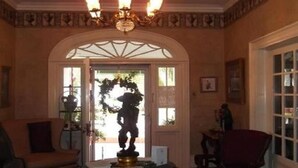 A room with a chandelier, a statue, and a red armchair.