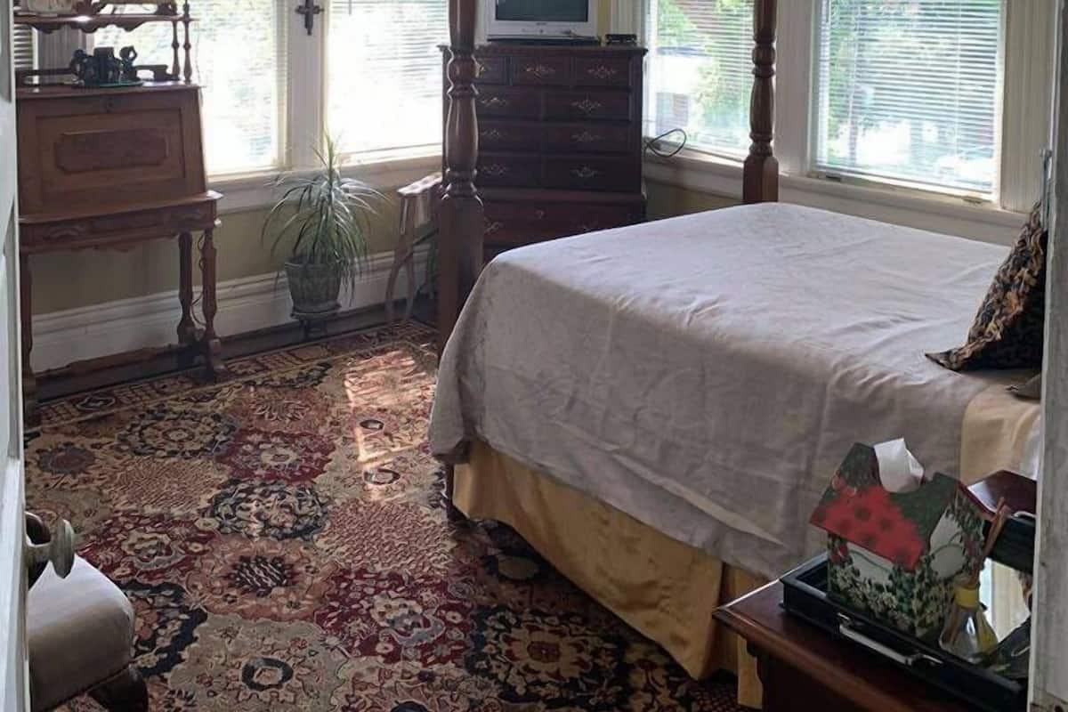 Ein Schlafzimmer mit Bett, Kommode, Fernseher und Deckenventilator.