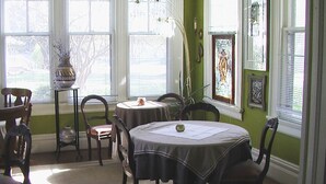 A dining area with a round table, chairs, a vase, and a window with a view.