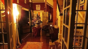 A narrow hallway with a rug, a table with a vase of flowers, and a staircase to the right.